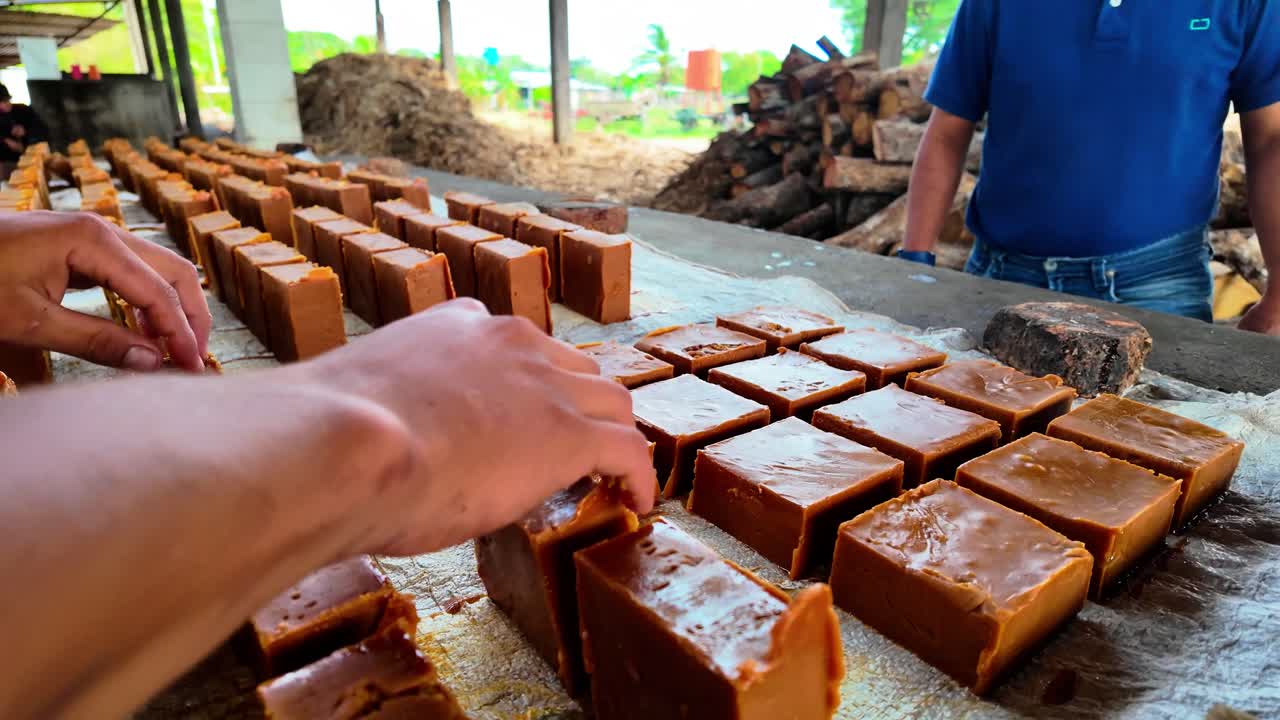 Man unmolding caramelized sugar blocks with hands in outdoor workshop setting