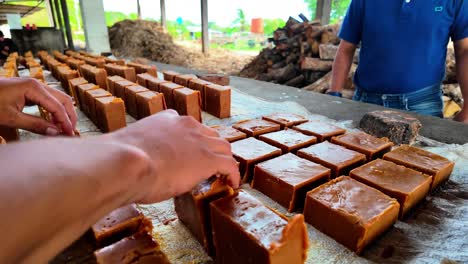 man unmolding caramelized sugar blocks with hands in outdoor workshop setting