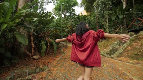 woman spinning with red jacket on natural park