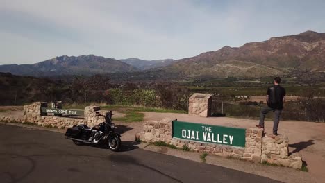 a motorcyclist stands overlooking the ojai valley of california