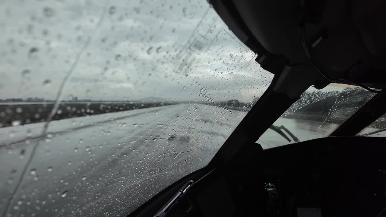 an immersive pilot’s view from Captain seat while taxiing along an airport taxiway for departure with stormy weather with rain showers.