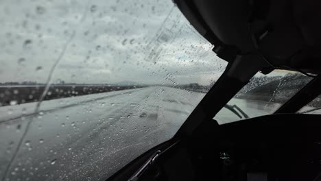 an immersive pilot’s view from captain seat while taxiing along an airport taxiway for departure with stormy weather with rain showers.