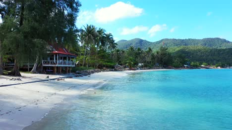 beach bar with sea view near palm trees and white sand washed by calm crystal water of turquoise lagoon on tropical island