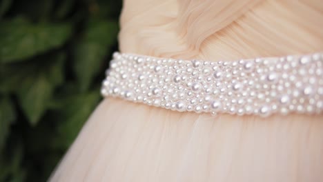 closeup view of beautiful wedding dress with pearls hanging on the tree branch. slowmotion shot