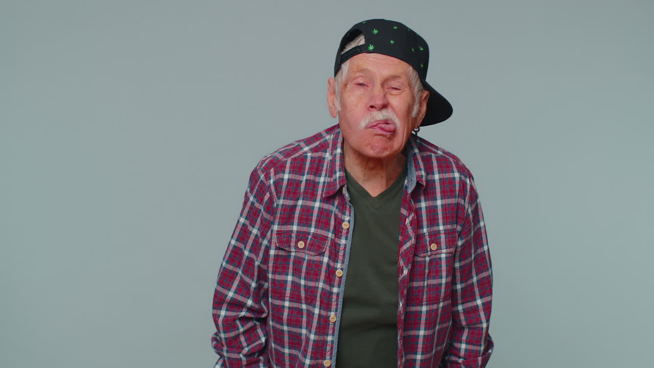 재미있는 남자가 혀를 보여주고 카메라에 얼굴을 만들고, 장난을 치고, 농담을 하고, 어리석은 얼굴로 원이를 만들고