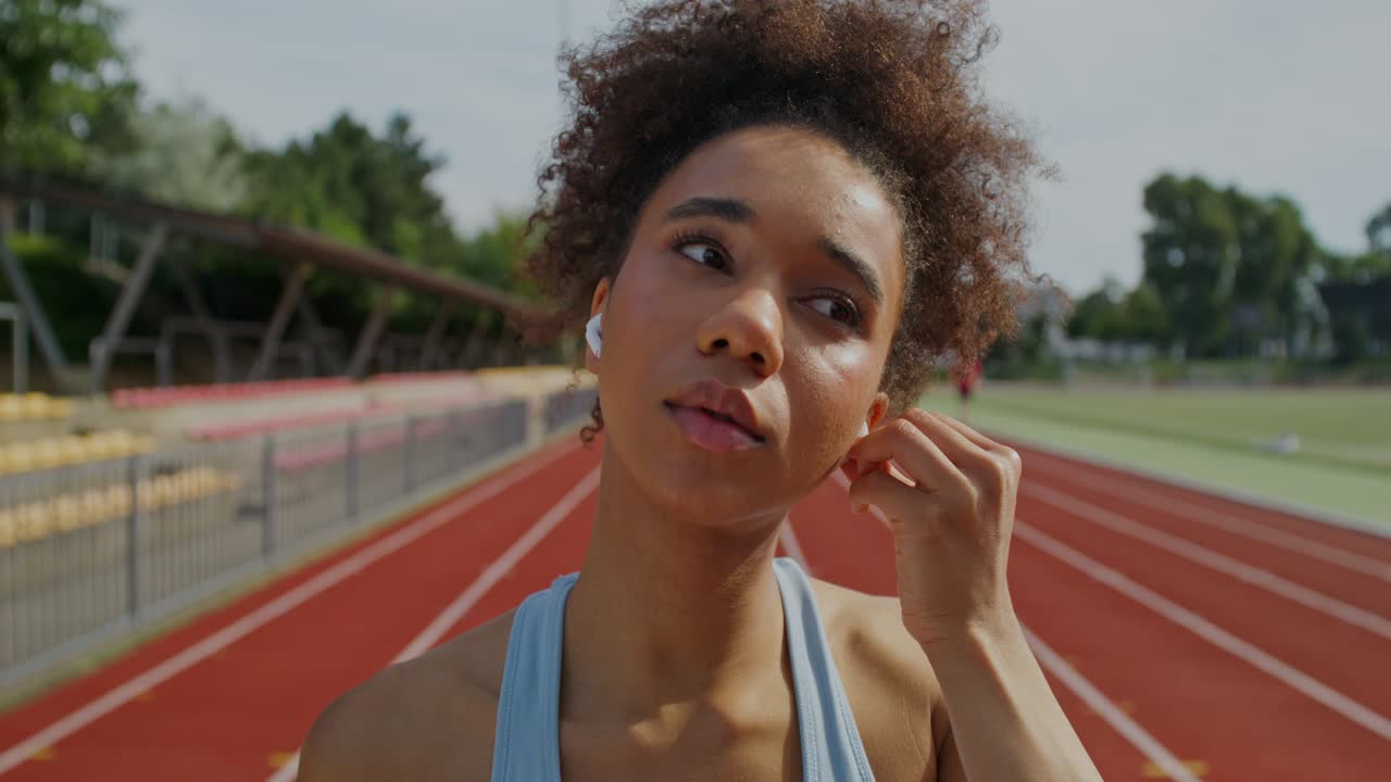 mujer ajustando auriculares y cabello en una pista de carrera