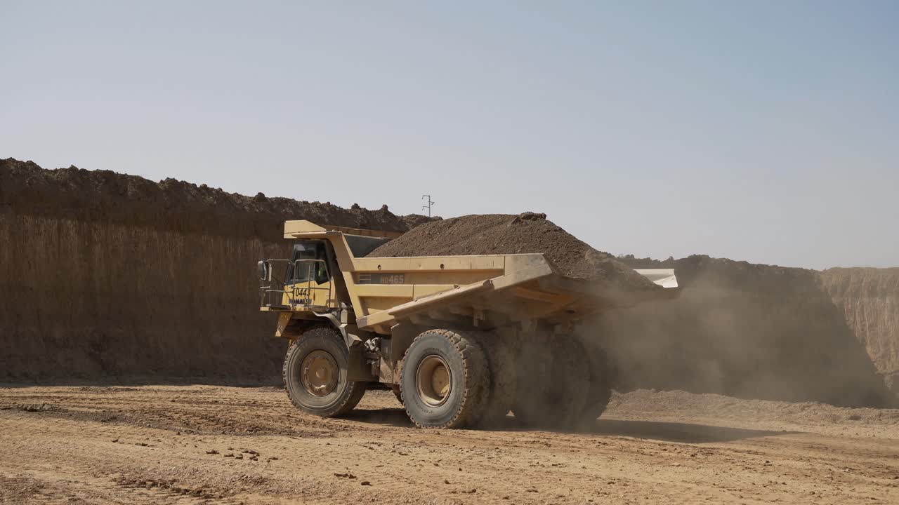 En stor lastbil fyldt med sand er på vej mod byggepladsen, luftfotos af lastbilen ved siden af byggepladsen og materialer.