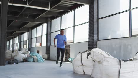 空の都市の建物を通ってジョギングするスポーツ服を着たアフリカ系アメリカ人男性