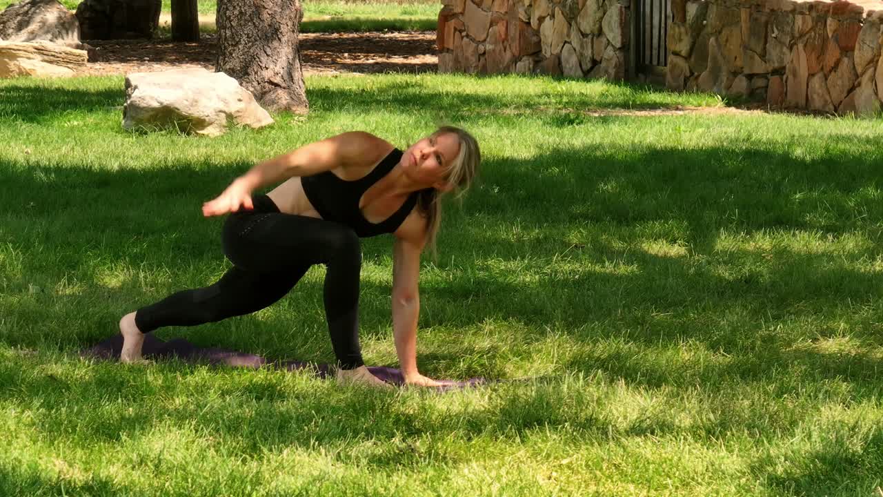 An agile woman demonstrates yoga poses in a public park. Drone 4k windy day