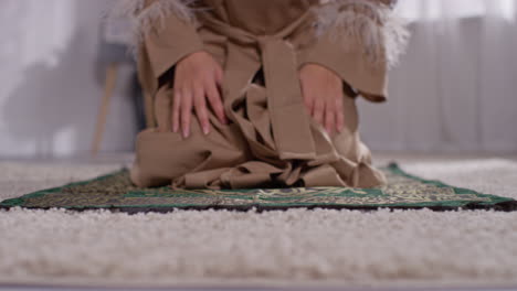 primer plano de una mujer musulmana con hijab en casa orando arrodillada en la alfombra de oración 3