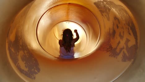 Blonde-girl-slides-down-yellow-tube-slide