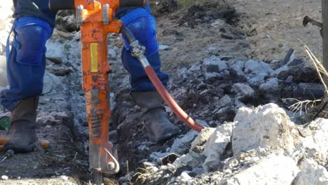 hombre limpiando escombros con una pala en la zanja por su martillo de jack cerca de la cámara