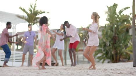 happy diverse group of friends dancing with sparklers at beach