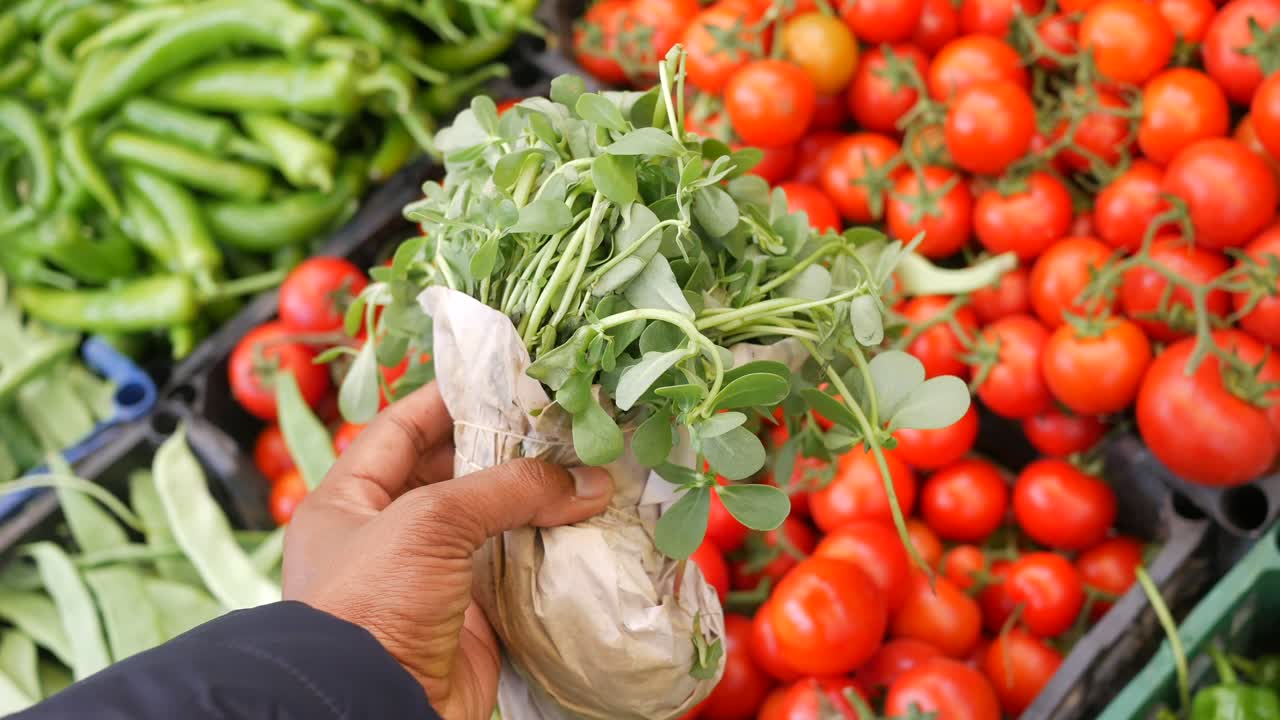 Hand holding a bunch of fresh herbs in a market