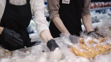 trabajadores felices con un delantal negro ordenan los productos y los ponen en un estante. trabajo en la tienda. días laborables. comida saludable. primer plano