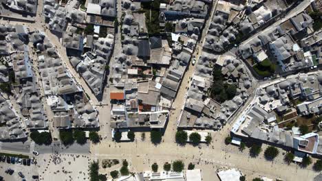 drone aérien haut plan large de petites rues piétonnes autour d'alberobello, italie