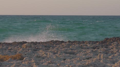 Toma-En-Cámara-Lenta-Del-Mar-Adriático-Con-Olas-Rompiendo-En-Las-Rocas-Y-Un-Hermoso-Cielo-Coloreado,-Agua-Turquesa-En-El-Sur-De-Italia.