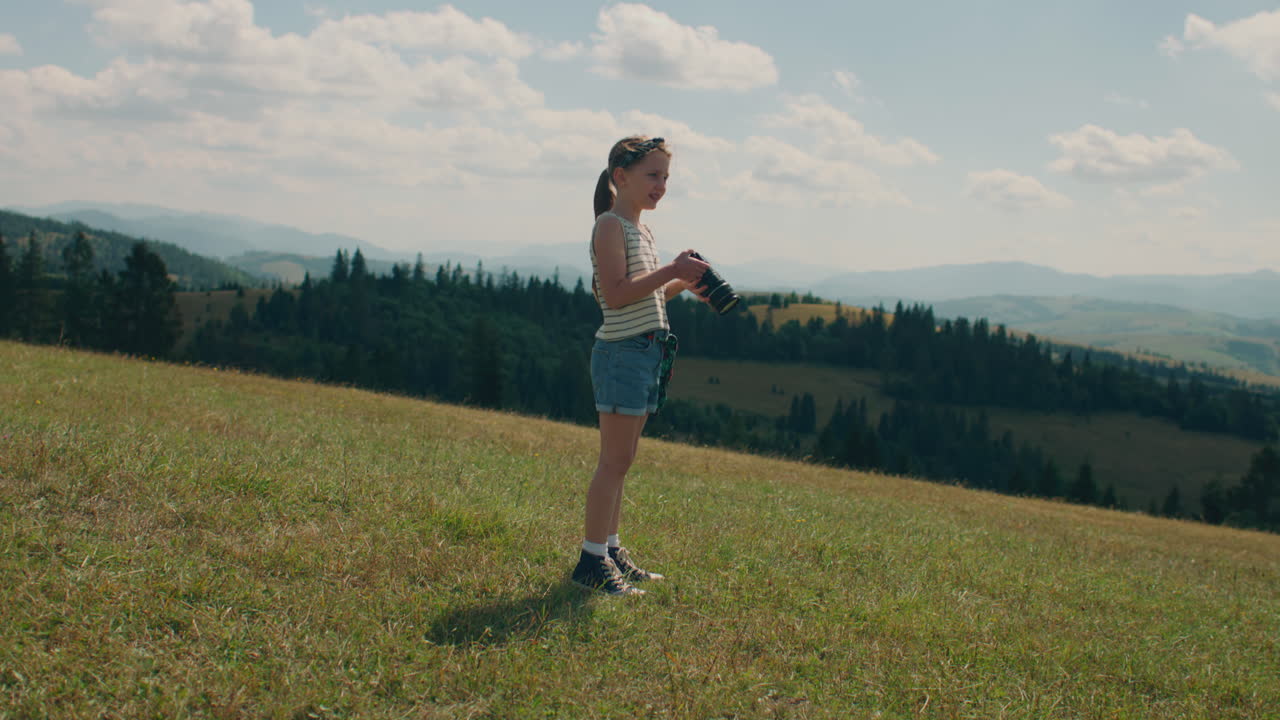 Young Girl Photographer Walking with Camera Young Photographer Walking with Camera on Grass Hill Girl Watching at Beautiful Landscape and Amazing Nature View Spending Leisure Time Outdoor Slow Motion front View