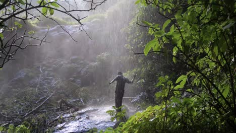 Zeitlupenaufnahme-Eines-Glücklichen-Afrikanischen-Mannes,-Der-Unter-Einer-Tropischen-Wasserfalldusche-Tanzt