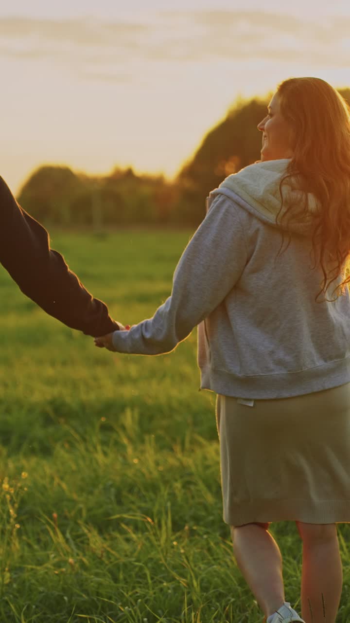 Couple Walking Hand in Hand in a Field at Sunset