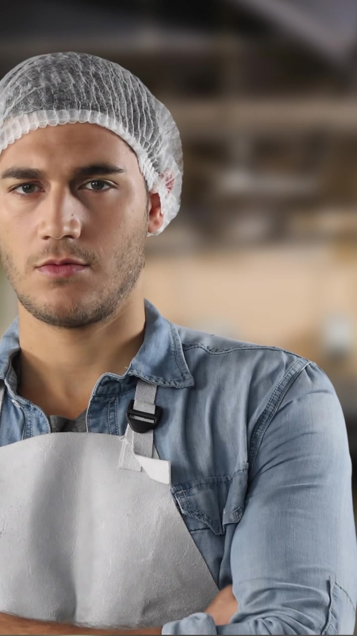 Kaukasischer Mann trägt Schutzkappe und weiße Schürze in einem Lagerhaus.
