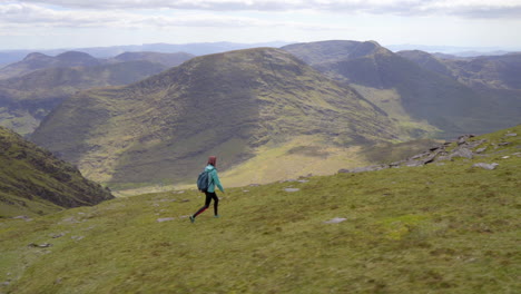 Lateral-tracking-shot-of-a-happy-girl-hiking-and-walking-on-the-high-mountain-trail-outdoor-in-nature-in-Ireland-at-Mcgillycuddy-Reeks-in-4K