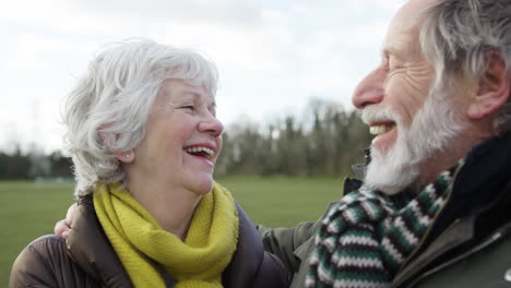 una pareja de ancianos riendo disfrutando del otoño o el invierno caminando juntos por el parque