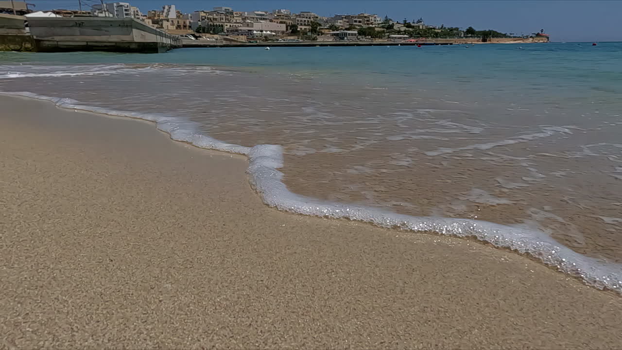 Ripresa dal basso al rallentatore di piccole onde su una spiaggia sabbiosa
