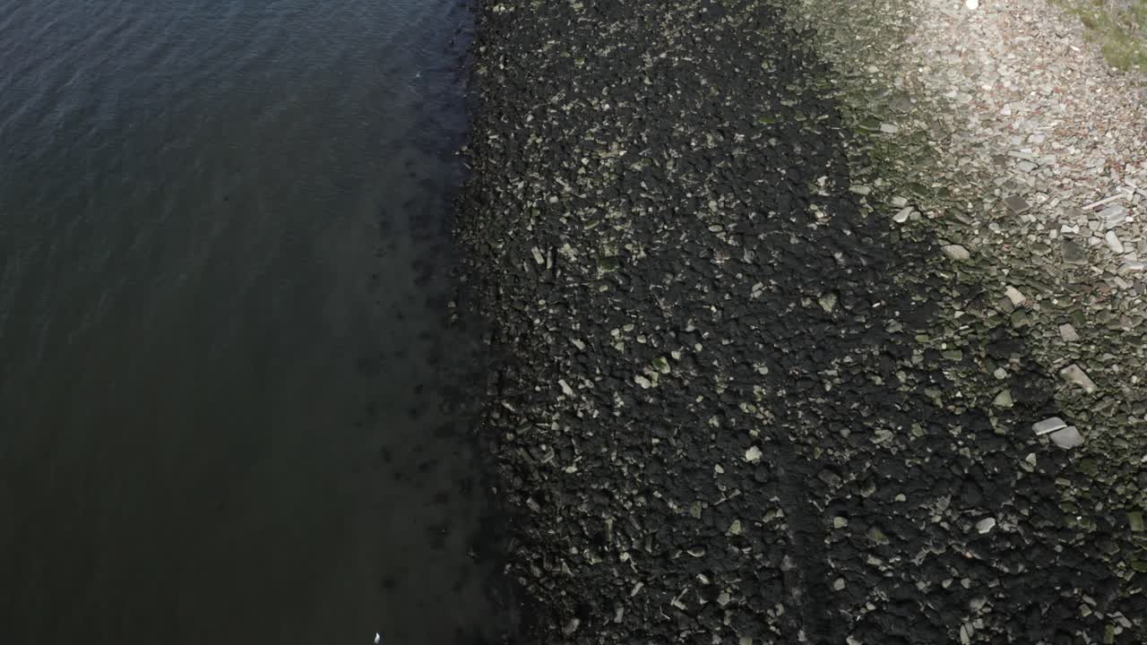 загрязненный пляж с черной нефтью, покрывающей скалы после разлива нефти из танкера | 4k at 30 fps