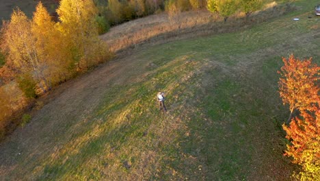 punto de vista aéreo uhd 4k de un hombre relajándose al aire libre en otoño. dron volando en círculo para capturar el sujeto