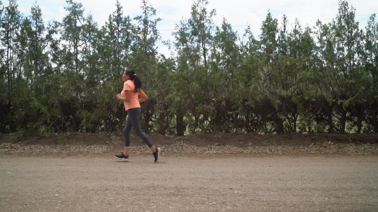una mujer está participando en una carrera dentro del parque - cámara lenta