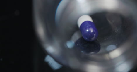 píldora médica única en botella pequeña girando sobre fondo negro 4