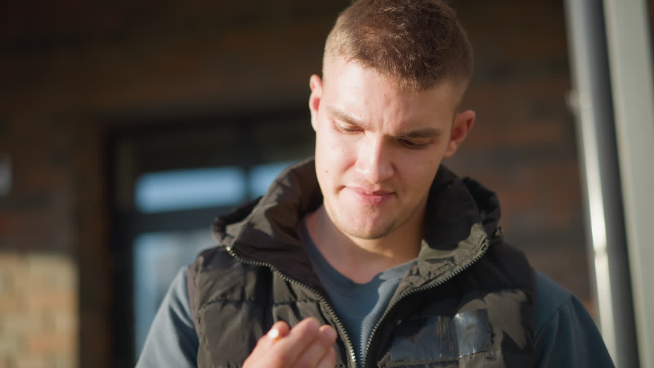 close up of young boy preparing to smoke pauses thoughtfully while holding cigarette then decides against it and throws it away with subtle expression of relief under soft natural light