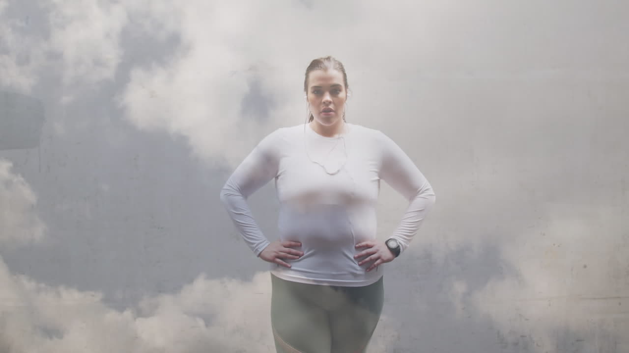 Animazione di nuvole su una donna caucasica taglia forte in abiti sportivi che flette i muscoli.