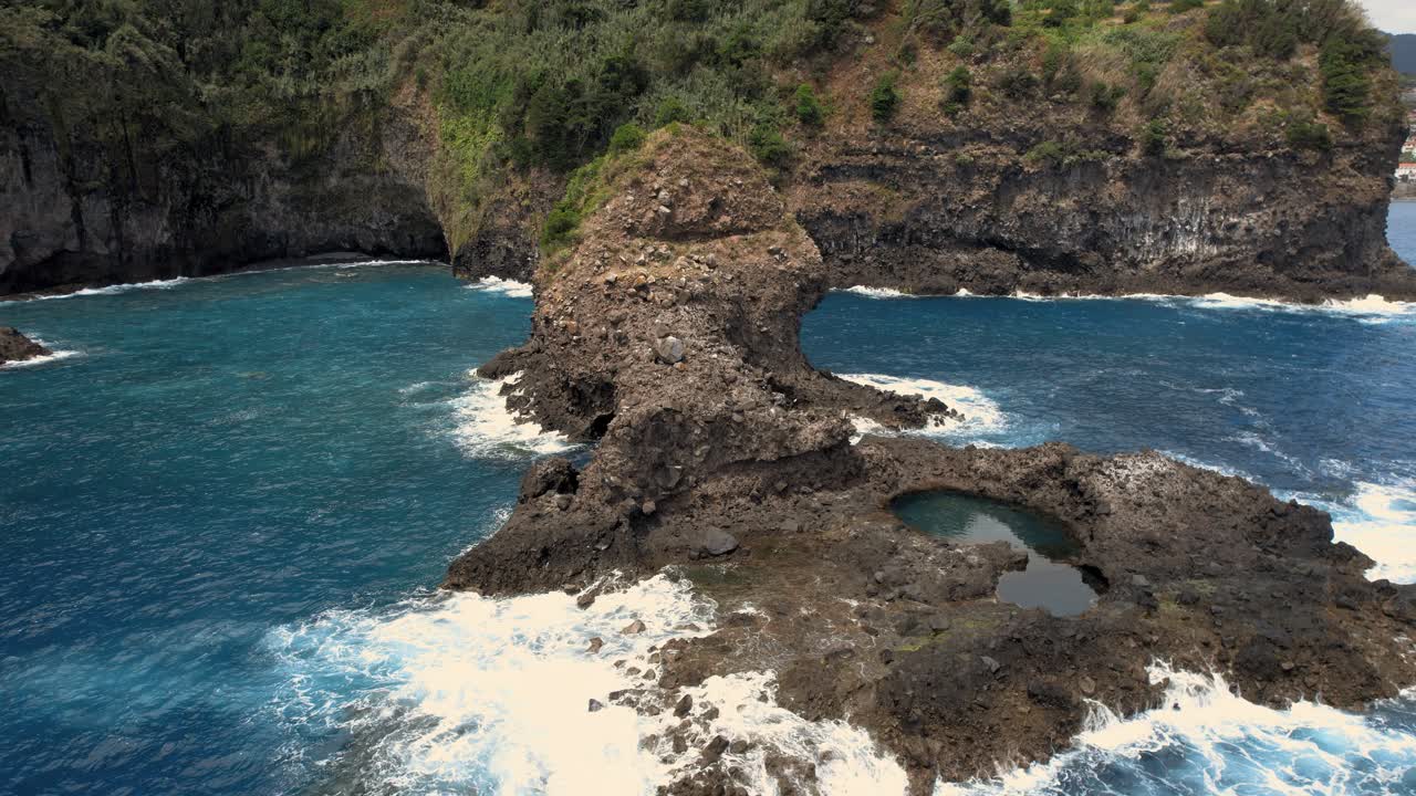 Small rock island reef with cave near ocean coast cliffs of Madeira