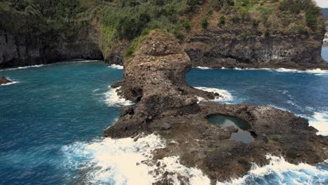 small rock island reef with cave near ocean coast cliffs of madeira