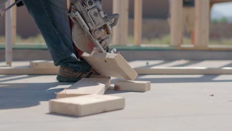 worker cuts wood using foot as leverage