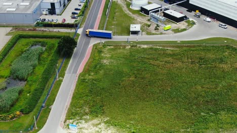 Semi-truck-with-cargo-trailer-is-travelling-along-a-parking-lot-of-a-warehouse-in-the-logistics-park