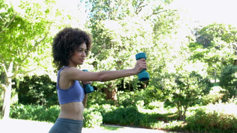 bruneta en forma trabajando con pesas en el parque