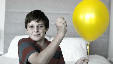 Boy-piercing-his-balloon-in-the-bedroom-in-selective-color