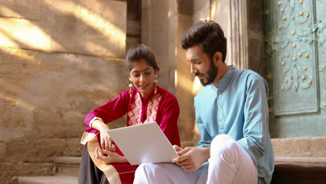 young indian couple sitting in front of a door