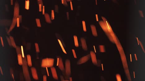 closeup of burning hot bonfire fire sparks. bright abstract dark background with fast moving burning particles leaving blurred trails