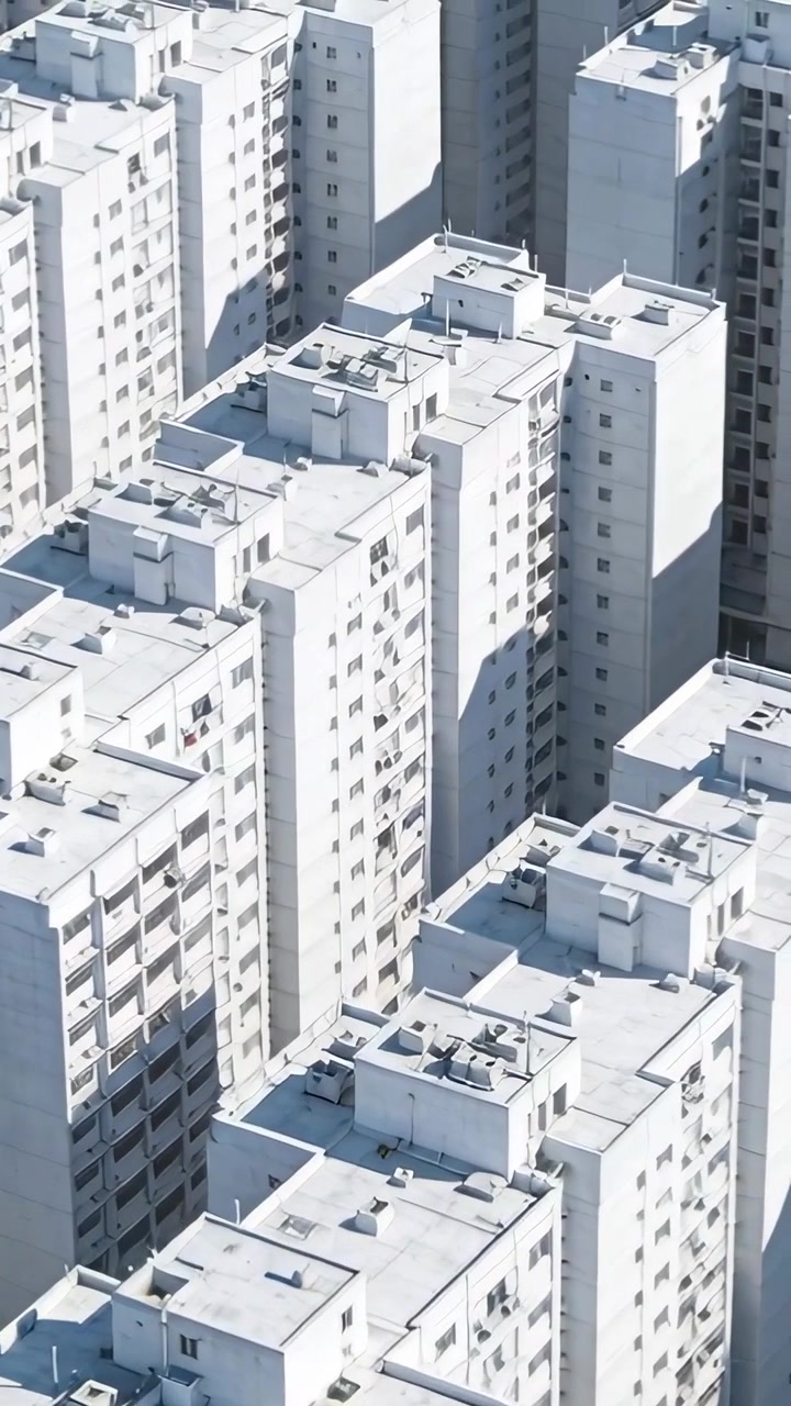 Video vertical: Cámara deslizándose hacia abajo sobre torres de apartamentos, revelando fachadas, sistemas de climatización
