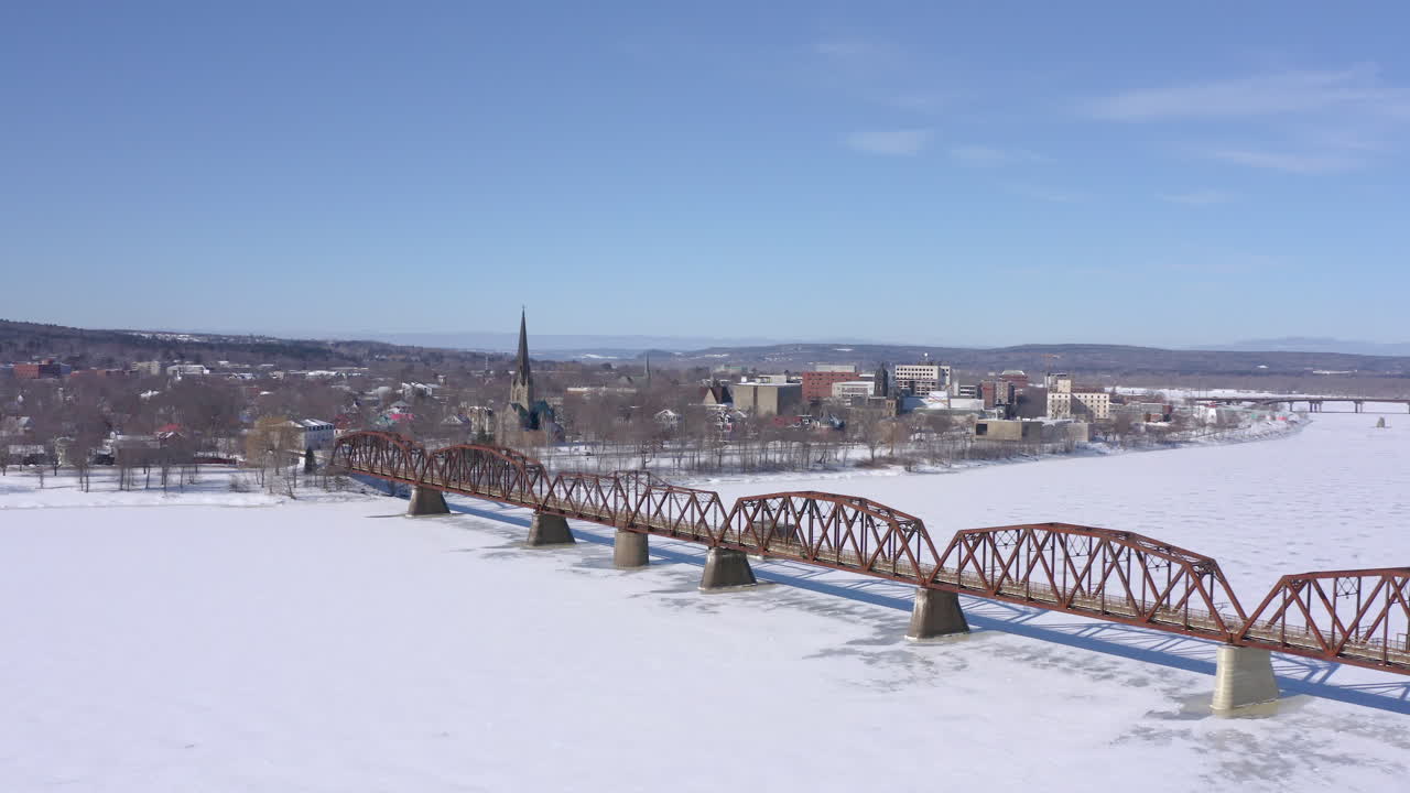 AERIAL: Wide Orbiting Clip Of Walking Bridge In Fredericton On Sunny Winter Day