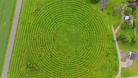 evergreen circle maze in countryside with drone ascending slowly, latvia, europe