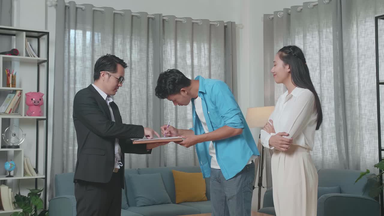 아시아인 남자가 팔을 고 서서 부동산 대리인과 손을 흔들고 있다.