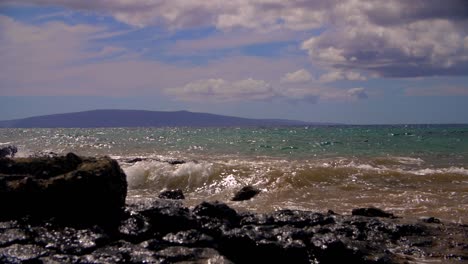 hawaii sand shore rock distant mountain and snorkeler slow motion