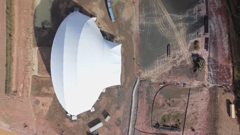 Top down establishing aerial pan of abandoned stadium construction site showing steel supports and beams
