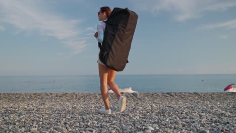 woman with a bag walking on a pebble beach