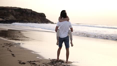 Couple-in-love.-Man-in-shirts-turning-around-his-lovely-woman-on-beach.-Full-length-view-of-happy-young-barefoot-man-and-woman